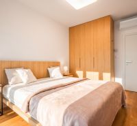 A bedroom with a double bed, a wardrobe, and a wooden decor floor in a two-room apartment.
