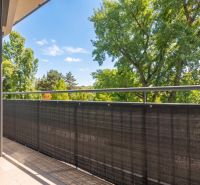 A balcony with a view of green trees in a 2-room apartment.