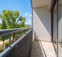 Balcony of a 2-room apartment with a view of greenery and blue sky.