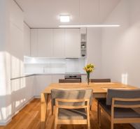 A kitchen in a 2-room apartment with a dining table and a wooden decor floor.
