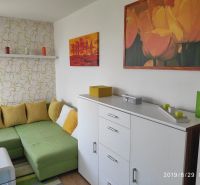 Living room with a sofa, wooden decor flooring, decorative paintings, and candles.