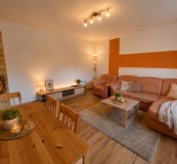 Living room in a 3-room apartment with a fireplace, an orange wall, and a floor with a wooden decor.