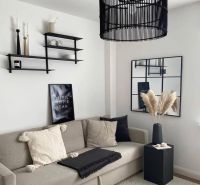 Living room in a family house with a comfortable sofa, decorative shelves, and a modern chandelier.