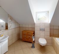 Bathroom with a bathtub and a sink, floor with wood decor, slanted ceiling.