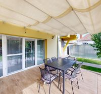 The terrace of a family house in Oľdza with a dining table under shading.