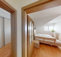 Bedroom with wood-patterned flooring in a family house, built-in wardrobe, bed.