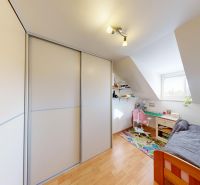 Children's room with wood-patterned flooring, built-in wardrobe, and desk in a family house.