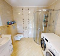 Bathroom in a family house with a sink, shower, washing machine, and dryer.