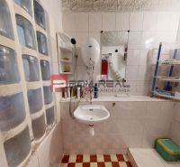 Bathroom in a cottage with a sink, shower, and shelves for toiletries.