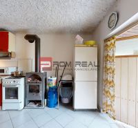 A kitchen in a cottage with red cabinets, a stove, and a fireplace, with a ceramic tile floor.