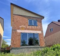 A family house in Cerová with an unfinished brick facade and large glass doors.