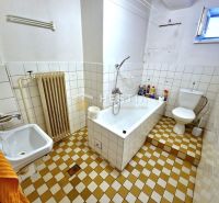 Bathroom with a bathtub and tiled floor in a family house.