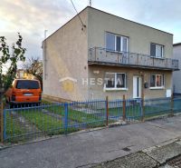 A family house in Senica with a flat roof, a balcony, and a parked orange car.