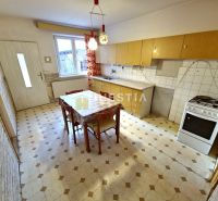 Kitchen in a family house with a dining table, light cabinets, and a gas stove.