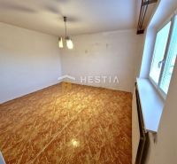 A room in a family house with a floor featuring a wooden decor and a large window.