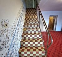 A staircase in a family house with a checkered tile pattern and a prominent railing.