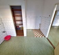 A kitchen with white tiles and an open pantry in a family house.