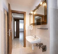 Bathroom with a sink in a three-room apartment with a wooden decor floor.
