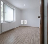 An empty room with a wood-patterned floor in a three-room apartment.