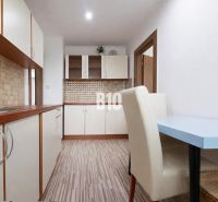 A kitchen in a 3-room apartment with a wooden decor floor and light furniture.