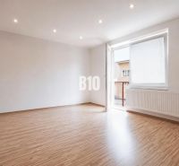 A spacious room in a 3-room apartment with a wooden decor floor and a large window.