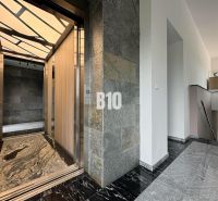 A hallway with a stylish elevator in a 2-room apartment, with stone walls and flooring.