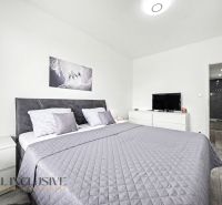 Bedroom in a 3-room apartment with a double bed, television, and floor with wooden decor.