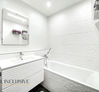 A bathroom with white tiles and a sink in a 3-room apartment.