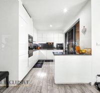 A kitchen in a 3-room apartment with white furniture and a wooden decor floor.