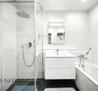 A bathroom with a modern shower and bathtub in a 3-room apartment with white tiles.