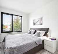 Bedroom in a 3-room apartment with a wood-patterned floor, a large bed, and a painting on the wall.