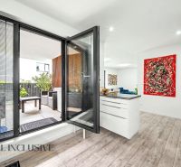 Interior of a 3-room apartment with a balcony, wooden decor flooring, and colorful art.