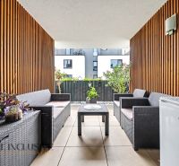 Furnished terrace of a 3-room apartment with rattan furniture and floral decorations.