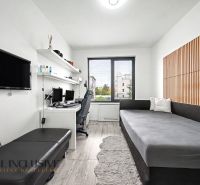 A room in a 3-room apartment with a desk, a sofa, and a wooden decor floor.