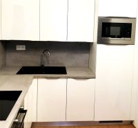 White kitchen with a microwave and built-in sink, 2-room apartment, floor with wood decor.