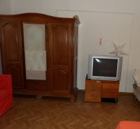 A room in a 2-bedroom apartment with wooden furniture and a wood-patterned floor.