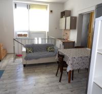 Living room in a two-room apartment with a wooden decor floor and simple furnishings.