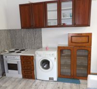 A kitchen in a 2-room apartment with an electric oven, washing machine, and a floor with a wooden decor.
