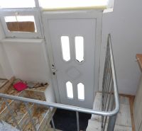 Stairs and entrance door in a 2-room apartment with a railing and mosaic tiles.