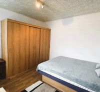 Bedroom in a 4-room apartment with a bed, wardrobe, and wooden decor flooring.