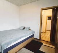 A bedroom in a 4-room apartment with a bed, carpet, and furniture with a wooden decor.