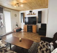 Living room in a 4-room apartment with a wooden decor floor and a TV on the wall.