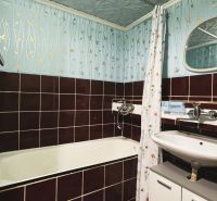 A bathroom with an enameled bathtub and tiled walls in a 4-room apartment.