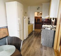 A kitchen in a 4-room apartment with a wood-patterned floor, a dining table, and appliances.