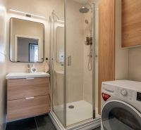 Bathroom in a 3-room apartment with a washing machine, shower, and sink with storage space.