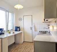 A kitchen in a family house with a wooden decor floor and white cabinets.