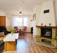 A room in a family house with a fireplace, a sofa set, and a floor with a wooden decor.
