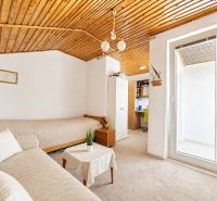 A room in a family house with a wooden ceiling, a sofa, and a workspace.