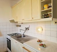 A kitchen in a family house with white cabinets and a counter, and a floor with a wooden decor.