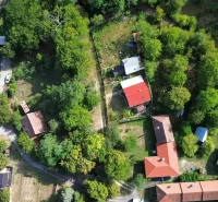 An aerial view of gardens and houses in Kolačno, surrounded by dense greenery.